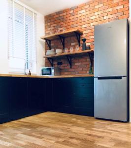 a kitchen with a refrigerator and a brick wall at Lofty & Apartamenty Garnizon Gdańsk in Gdańsk
