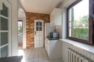 una cocina con armarios blancos y una pared de ladrillo en RETRO HOUSE, en Sztutowo