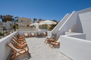 a patio with chairs and umbrellas on a balcony at Olive Tree Suites in Fira