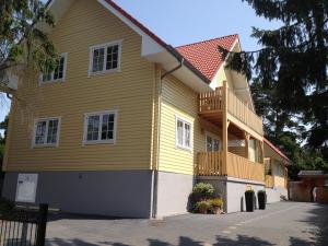 Cette maison jaune dispose d'une terrasse couverte et d'un balcon. dans l'établissement Haus Stoertebeker Appartements - Hotel Garni, Seebad Lubmin, à Lubmin