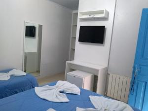 Habitación con 2 camas, TV y puerta azul. en Pousada Recanto Alpino, en Gramado