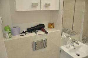 a bathroom with a sink and a hair dryer on a shelf at Mario Rooms in Warsaw