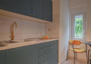 a kitchen with blue cabinets and a sink and a chair at Apartments Lucija in Zadar