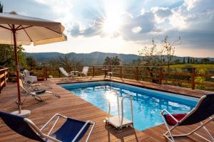 una piscina en una terraza con sillas y sombrilla en La Capannaccia en Scandicci