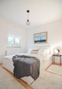 a white bedroom with a white bed and a rug at Apartments Lucija in Zadar