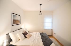 a bedroom with a bed with white sheets and pillows at Apartments Lucija in Zadar