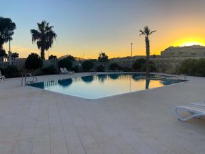 a large swimming pool with a sunset in the background at Casa Bonita Médano in El Médano