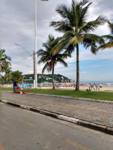 Ein Mann auf einer Bank neben dem Strand in der Unterkunft Guaruja - Enseada in Guarujá
