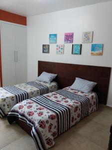 2 Betten in einem Zimmer mit Bildern an der Wand in der Unterkunft Guaruja - Enseada in Guarujá