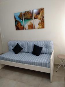 eine blaue Couch mit drei Gemälden an der Wand in der Unterkunft Guaruja - Enseada in Guarujá
