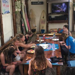 un grupo de chicas sentadas alrededor de una mesa comiendo comida en Sapa Inka, en Montañita