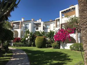 duży biały budynek z różowymi kwiatami na dziedzińcu w obiekcie Marbella - Estepona beach frontline apartment w mieście Estepona