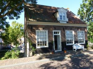 una casa de ladrillo con un banco blanco delante de ella en De Vier Kroonen, en Enkhuizen