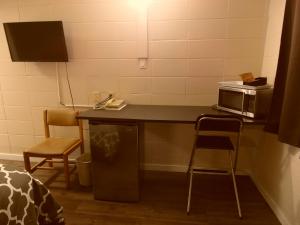 une cuisine avec un comptoir, un four micro-ondes et des chaises dans l'établissement West View Motel, à Hanna
