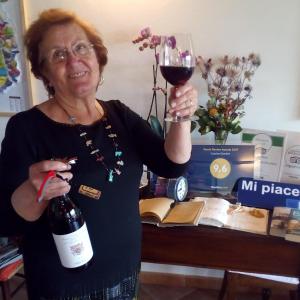Eine Frau, die ein Glas Wein hochhält. in der Unterkunft Cascina Giardini in Alba