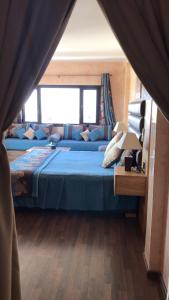 um quarto com uma cama azul e um sofá em Studiotel Afoud em Agadir