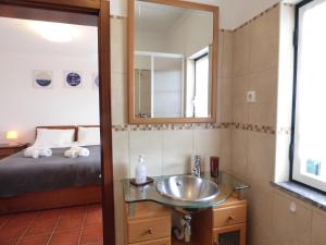 a bathroom with a sink and a bed and a mirror at Casa Margmar in Vila Nova de Milfontes