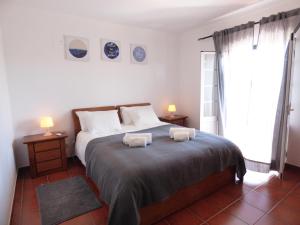 een slaapkamer met een bed met twee handdoeken erop bij Casa Margmar in Vila Nova de Milfontes