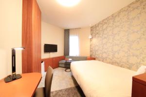 東京にあるリッチモンドホテル東京目白のベッド、デスク、テレビが備わるホテルルームです。