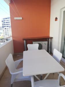 Biały stół i krzesła w pokoju z pomarańczową ścianą w obiekcie Flamingo Apartment w mieście Portimão