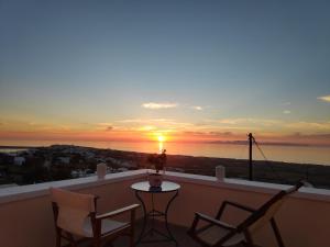 a sunset on a balcony with chairs and a table at Sunset Paradise Oia in Oia