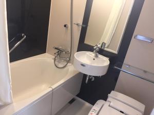 a white bathroom with a sink and a toilet at Richmond Hotel Yokohama Ekimae in Yokohama