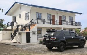 ein schwarzer SUV vor einem Haus geparkt in der Unterkunft Gregorio Homes in Bauang