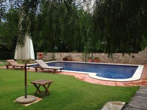 ein Pool mit zwei Bänken und einem Sonnenschirm in der Unterkunft Mas Falgarona Hotel Boutique & SPA in Avinyonet de Puigventós