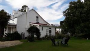 a white house with chairs and a table in the yard at Western House B&B Kurow in Kurow
