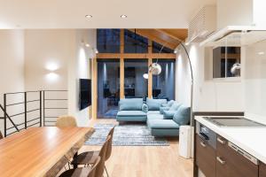 白马村Black Crane Chalet by Hakuba White Fox Company的配有桌子和沙发的厨房和客厅