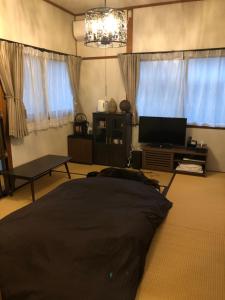 a living room with a bed and a television at Guest House "Ro"kumano in Shimonoseki