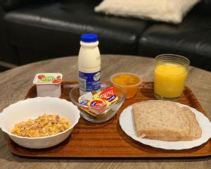 a tray with a plate of bread and a bottle of milk at Wrights by the Sea Motel in Paraparaumu Beach