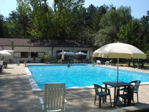 a pool with a table and chairs and an umbrella at Rio Verde camping villaggio in Costacciaro