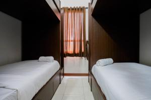 deux lits jumeaux dans une chambre avec fenêtre dans l'établissement Best Price 2BR at Taman Melati Margonda Apartment By Travelio, à Depok 9 autres photos
