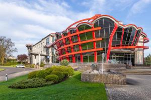 un gran edificio con una estructura roja delante de él en Hotel Olympic, en Wronki