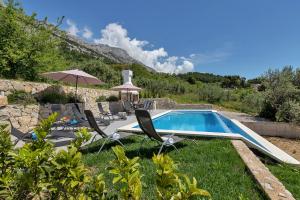 a pool with chairs and an umbrella in a yard at Villa NiMa in Brela