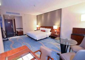 
a hotel room with a bed, table, chairs and a television at Gumaya Tower Hotel in Semarang
