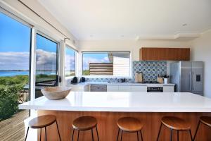 a kitchen with a large white island with wooden stools at Culburra Beachhouse in Greenwell Point