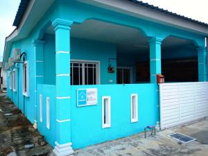 una casa azul con una puerta blanca y columnas en AZURE SKY HOMESTAY KUALA SELANGOR en Kuala Selangor