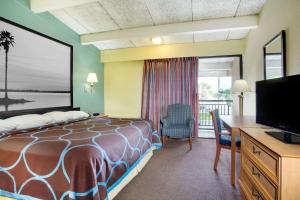 Habitación de hotel con cama, escritorio y TV. en Super 8 by Wyndham St. Augustine, en St. Augustine