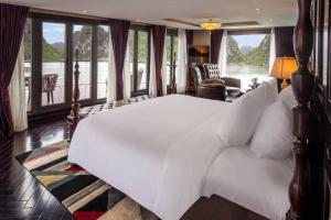 a bedroom with a large white bed with a view of the water at Ambassador Halong Cruise in Ha Long