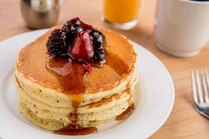 a stack of pancakes with berries on a white plate at Hotel Plaza del Sol in Hermosillo