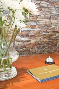 un vaso con fiori bianchi su un tavolo accanto a un libro di San Isidro Plaza Hotel a San Isidro