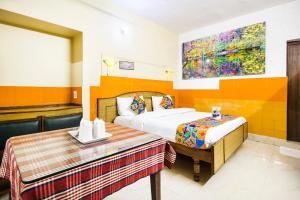 a bedroom with a bed and a table and a painting at Hotel Ashrey in Dehradun