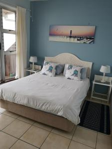a blue bedroom with a bed with white sheets and pillows at 21 Camarque in Umdloti