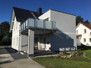 uma casa branca com uma varanda ao lado em Ferienhaus _GlueckSEEligkeit_ em Großkoschen
