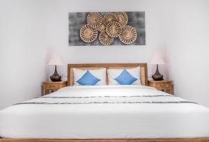 a bedroom with a large white bed with blue pillows at Umalas Suites in Seminyak