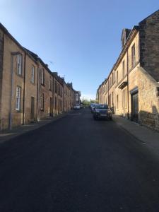an empty street with buildings and a car parked on the street at Upper Howick Hideaway in Alnwick