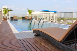 a swimming pool with a chaise lounge on a balcony at JVK Park Hotel in Cochin