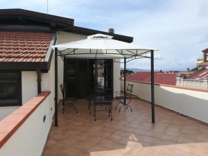 a patio with chairs and an umbrella on a roof at Fata Morgana Suite in Reggio Calabria